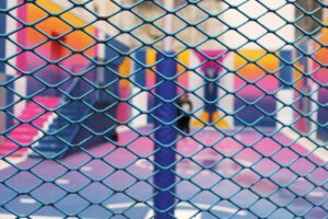 Decorative image representing safeguarding, a school playground and fence in the foreground.