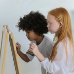 two children drawing on an easel side by side
