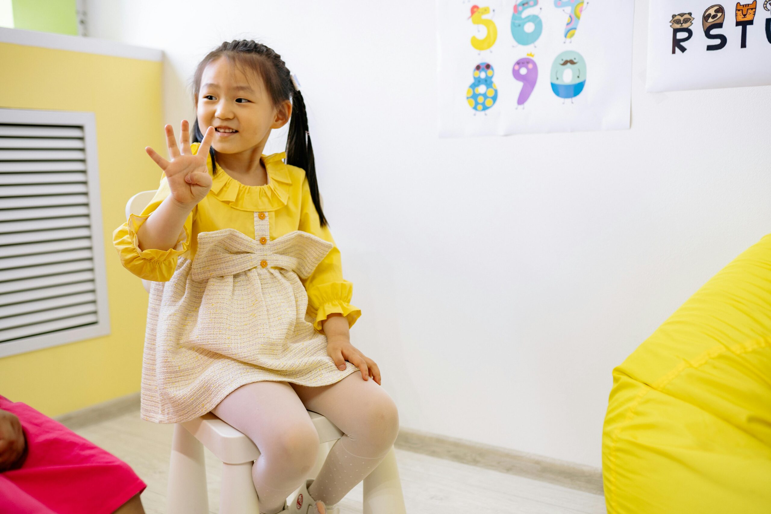 pexels-yankrukov-8613106 Girl in Yellow and White Dress Learning To Count With Her Fingers