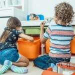Two children playing with toys with their backs to the camera.