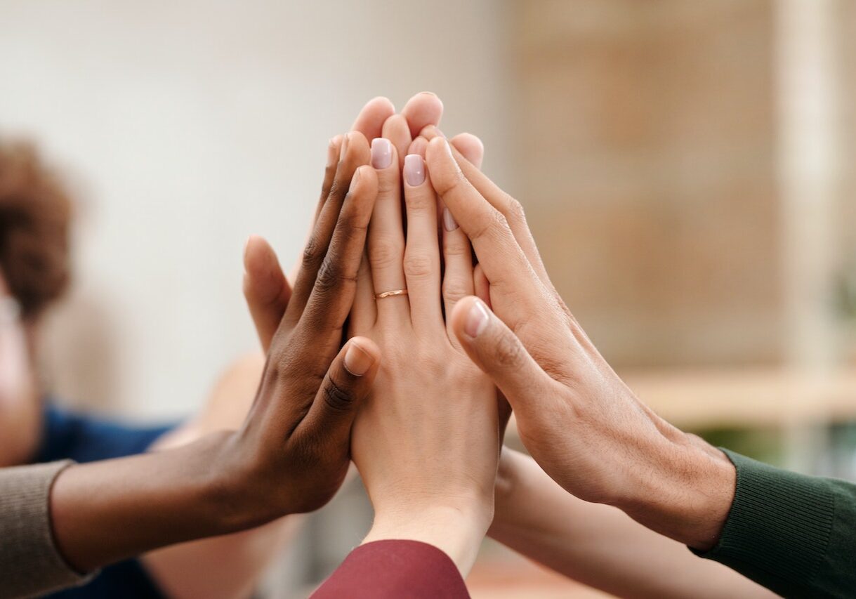 Decorative image to represent a four way partnership of four people 'high fiving'.