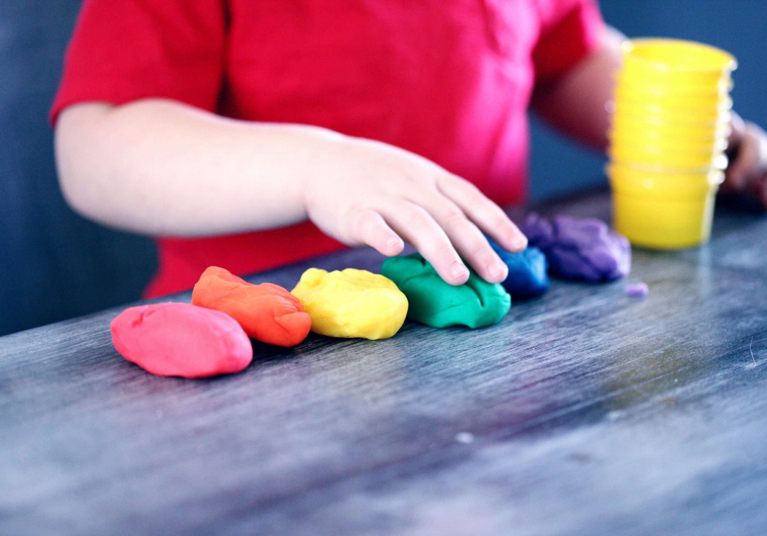 pexels-mccutcheon-1449934 child lining up coloured balls of clay