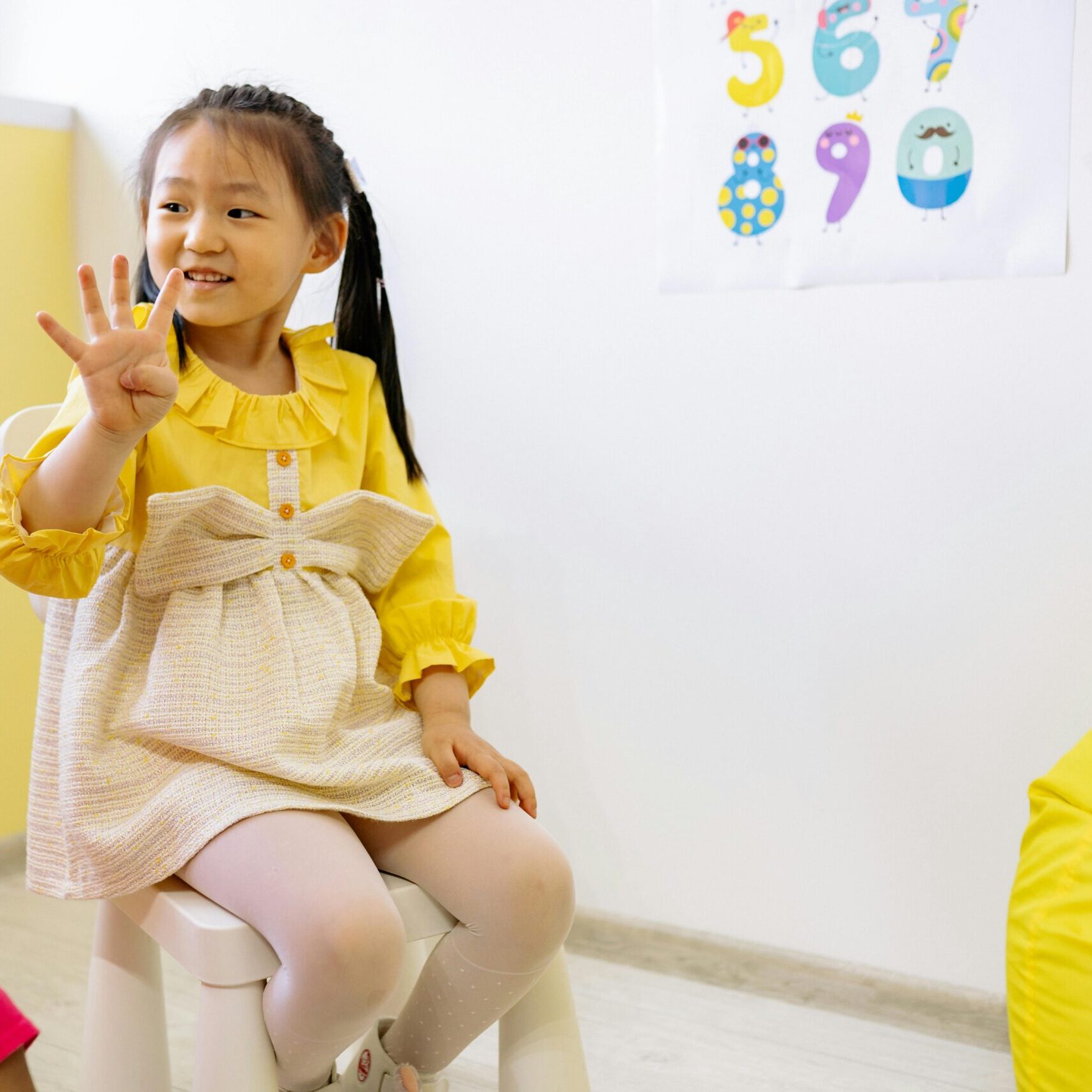 Girl in Yellow and White Dress Learning To Count With Her Fingers